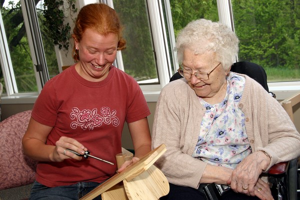 Jeune femme bénévole construisant un projet en bois avec une femme résidente