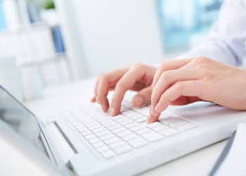 close up of hands of a nurse typing on laptop